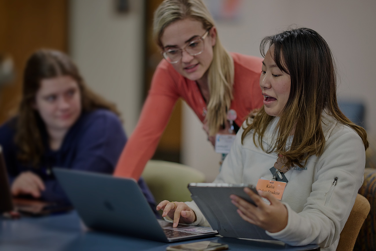 Nursing students studying with faculty member helping.