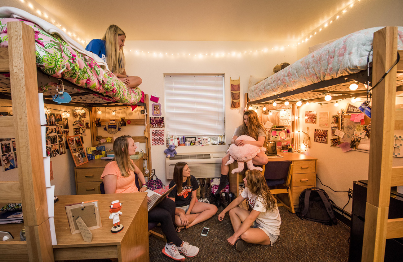 Five female students hanging out and talking in an dorm room in the NLC