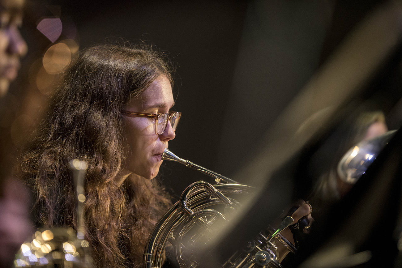 a student playing the french horn at a band performance