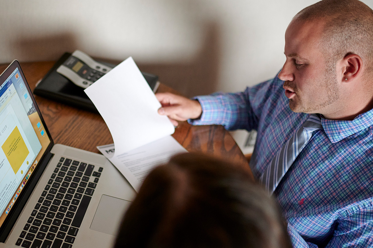 Male administrator looking over a document and discussing with an individual