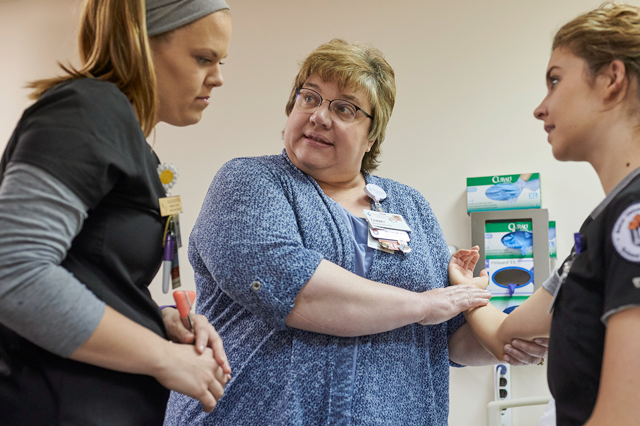 Nursing professor demonstrating the arm of a female nursing student