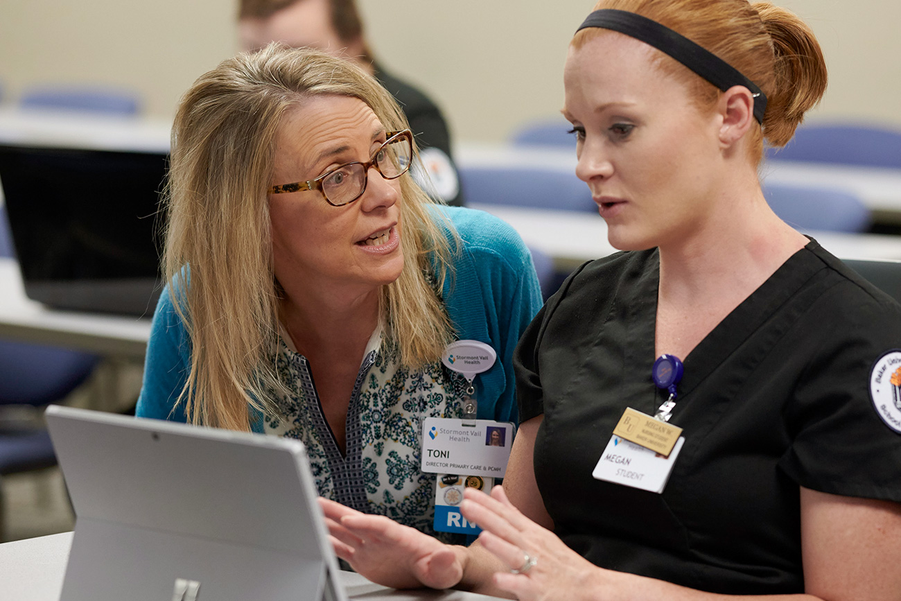 nursing professor talking one on one with female student in class