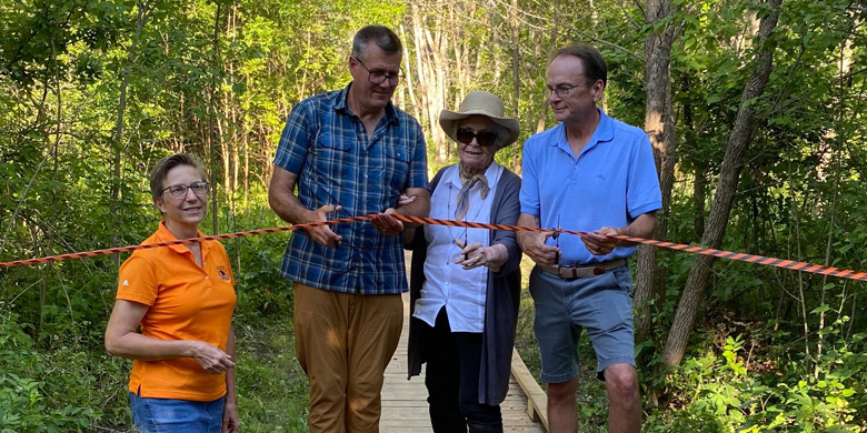 Four people cutting the ribbon at the boardwalk