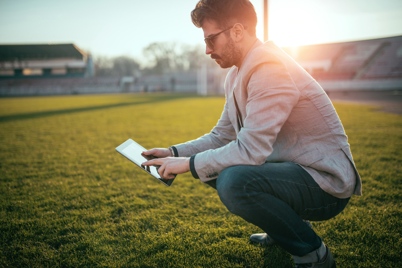 student looking at ipad on football field