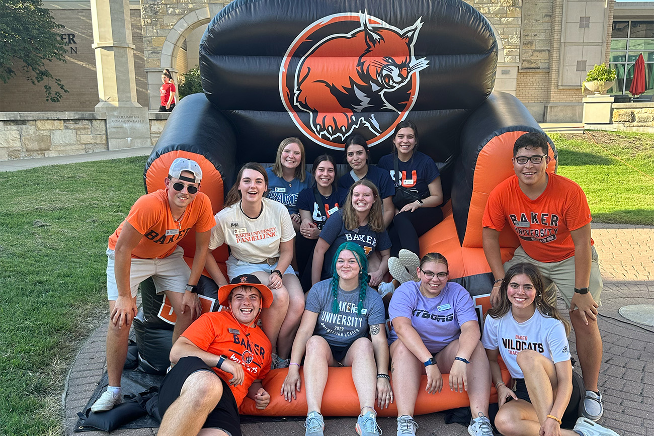 11 Baker students sitting on giant inflatable chair that has the Wildcat logo on it.