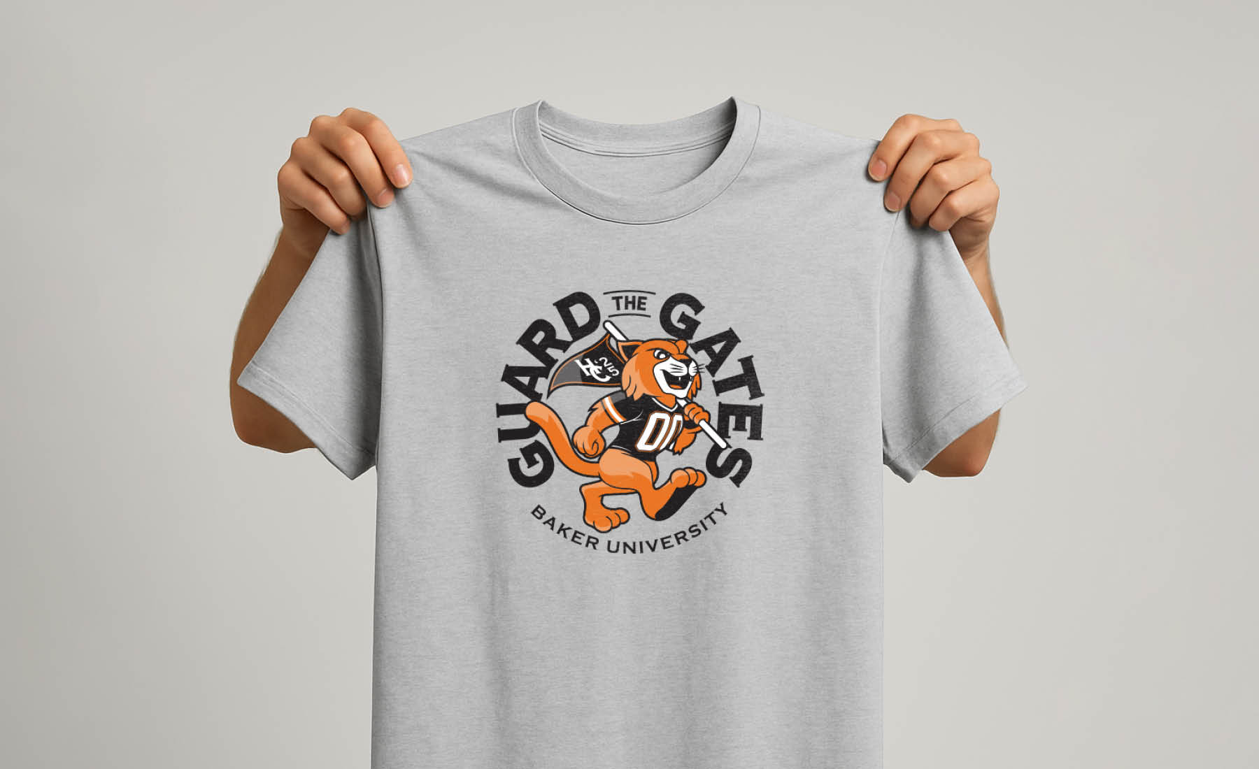 Hands holding the limited edition Baker University 2025 Homecoming T-shirt. Only available in the Wildcat Wearhouse.